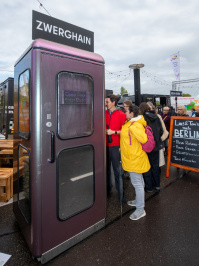 Kleine Disco-Kabine „Zwerghain“ als kreative Attraktion im Berlin-Bereich des Bürgerfests, Besucher warten vor dem Eingang.