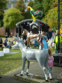 Bunte Statue der Bremer Stadtmusikanten mit Esel, Hund, Katze und Hahn aufeinander, im Hintergrund Bühne und Besucher.