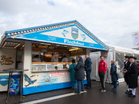 Verkaufsstand „Fischhus“ bietet Backfisch und Fischspezialitäten aus Bremerhaven, Besucher stehen in der Schlange.