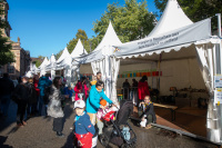 Reihe von Informationszelten mit Vereinen und Initiativen aus dem Saarland, Besucher spazieren über das Bürgerfest.