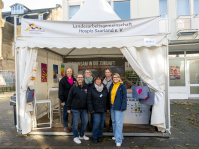 Stand der Landesarbeitsgemeinschaft Hospiz Saarland e. V. beim Bürgerfest in Saarbrücken, Teammitglieder posieren vor dem Pavillon.