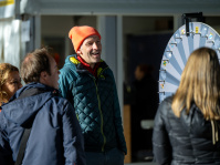 Besucher mit orangefarbener Mütze lacht beim Glücksrad-Spiel am Stand der Bundesregierung.