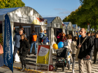 Besucherinnen und Besucher informieren sich am Pavillon des Bundesministeriums für Wirtschaft und Energie, bunte Luftballons und Kinderwagen prägen das Bild.