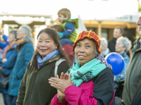 Zuschauerinnen klatschen bei einer Bühnenaufführung, eine Frau trägt bunte Strickmütze und Stofftasche.
