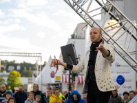 Straßenkünstler im weißen Sakko führt Zaubertrick mit Seilen vor, Publikum beobachtet aufmerksam die Vorstellung.