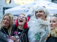 Gruppe junger Frauen posiert lachend mit einem Mann in weißem Papierkostüm