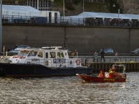 Polizeiboot WSP 4 liegt an der Saar, daneben DLRG-Rettungsboot mit Einsatzkräften in roten Anzügen.