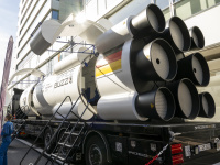 Nachbau einer großen Rakete mit der Aufschrift „Space Buzz“ auf einem LKW, umgeben von Besucherinnen und Besuchern.