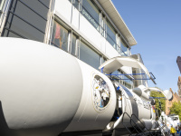 Modell einer Rakete „Space Buzz“ vor einem modernen Bürogebäude mit Zuschauern und Fahnen.