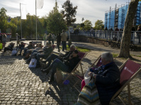 Besucherinnen und Besucher sitzen in Liegestühlen mit der Aufschrift „Bundesrat“ auf einem gepflasterten Platz.