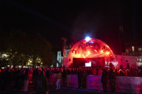 Konzertbühne in Rotlicht bei Nacht, Menschenmenge schaut auf den Künstler auf der Bühne.