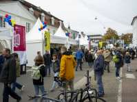 Menschen flanieren an weißen Pavillons mit spitzen Dächern vorbei