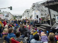 Straße mit zahlreichen Infoständen und bunten Luftballons, Besucherinnen und Besucher flanieren zwischen den Zelten.
