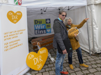 Infozelt mit Plakaten „Ich höre dir zu“ und Menschen vor dem Stand
