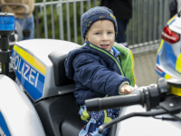 Kind mit Mütze sitzt auf einem Polizeimotorrad