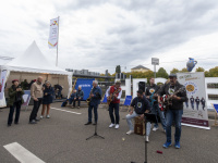 Musiker spielen mit Gitarren und Saxophon vor einem Hessen-Zelt im Freien.