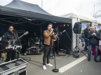 Band spielt Musik unter einem schwarzen Pavillon, Sänger mit Mikrofon im Vordergrund.