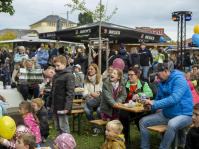 Menschen sitzen und stehen dicht gedrängt, Kinder mit Luftballons im Vordergrund.