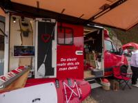 Roter Infostand mit SUP-Board, Paddel und Schriftzug „Da steckt mehr drin, als man denkt“ bei einer Veranstaltung.