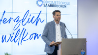 Eine Gruppe Menschen posiert vor einer Tafel für ein Gruppenbild 