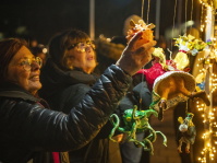 Zwei Frauen betrachten lächelnd bunte, handgemachte Figuren an einem beleuchteten Stand.