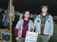 Zwei Pfadfinder präsentieren ein beschriftetes Schild vor ihrem geschmückten Jurtenstand.