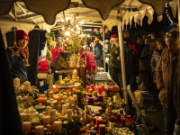 Ein stimmungsvoll dekorierter Stand mit Kerzen und Adventskränzen, umgeben von vielen Besuchern.