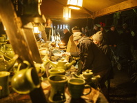 Menschen stöbern an einem Keramikstand voller handgefertigter Tassen, Krüge und Schalen.