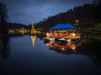 Die Wasserbühne und ein schwimmender Lichterbaum spiegeln sich im dunklen Weiher.