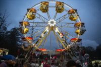 Ein großes, hell erleuchtetes Riesenrad dreht sich vor dem abendlichen Himmel und zieht zahlreiche Besucher an.