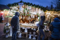 Ein liebevoll dekorierter Stand mit weißen Weihnachtsartikeln, Engeln, Kränzen und winterlichen Dekorationen, umgeben von Besuchern.