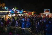 Dichte Menschenmenge zwischen Essensständen, begleitet von Musik, Lichtern und weihnachtlicher Stimmung.
