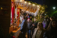 Besucher stehen vor einem festlich geschmückten Holzstand und bestellen warme Speisen zur Adventszeit.