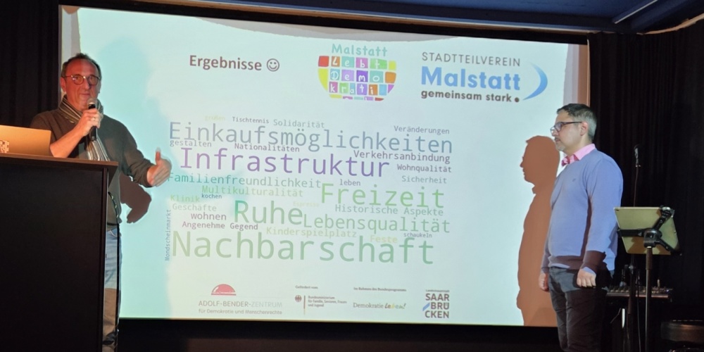 Ein Mann mit Mikrofon vor einer Leinwand