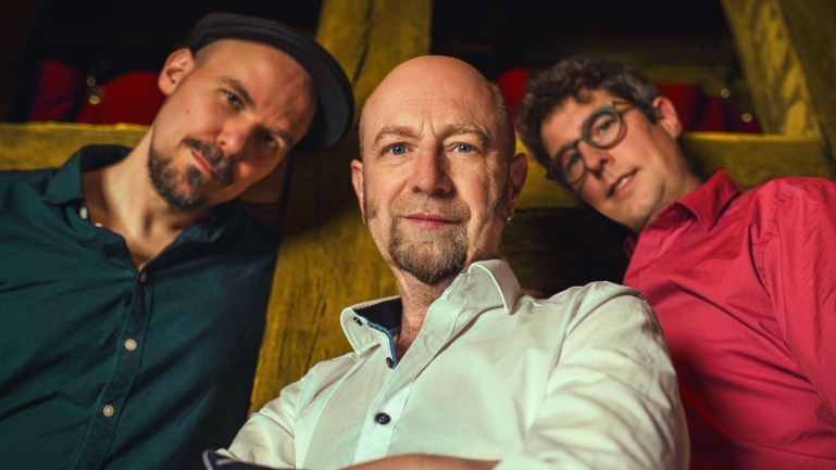 Drei Männer in blauem, weißem und rotem Hemd schauen nach unten in die Kamera Drei Männer in blauem, weißem und rotem Hemd schauen nach unten in die Kamera