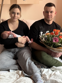 lternporträt im Krankenhauszimmer: Felicitas Benoit hält Neujahrsbaby Malia im Arm, Vater Alexej Bernowsky sitzt daneben mit einem Blumenstrauß.