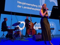 Eine Band auf einer Bühne, dahinter eine Leinwand mit blauem Motiv