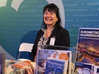 Eine Frau steht lächelnd an einem Stand