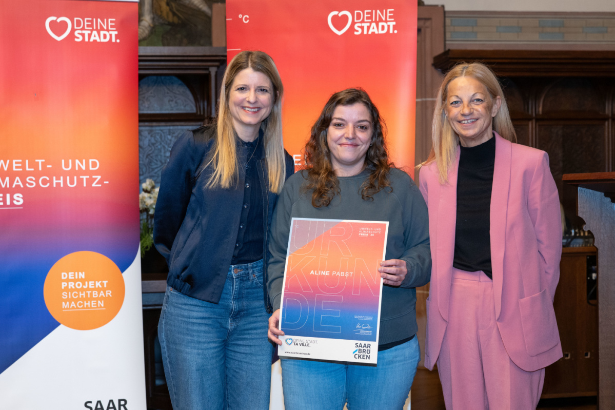 Preisträgerin hält Urkunde in Kamera und lächelt