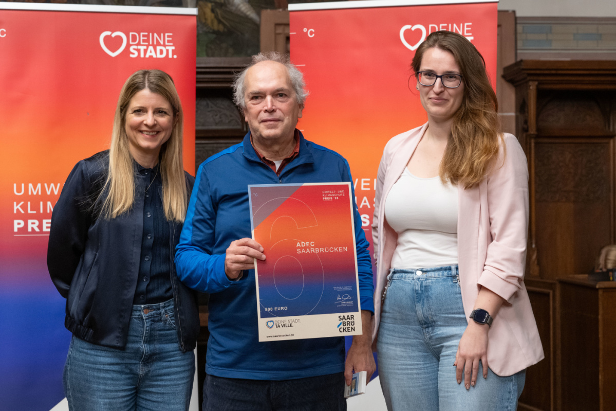 Preisträger hält Urkunde in Kamera und lächelt