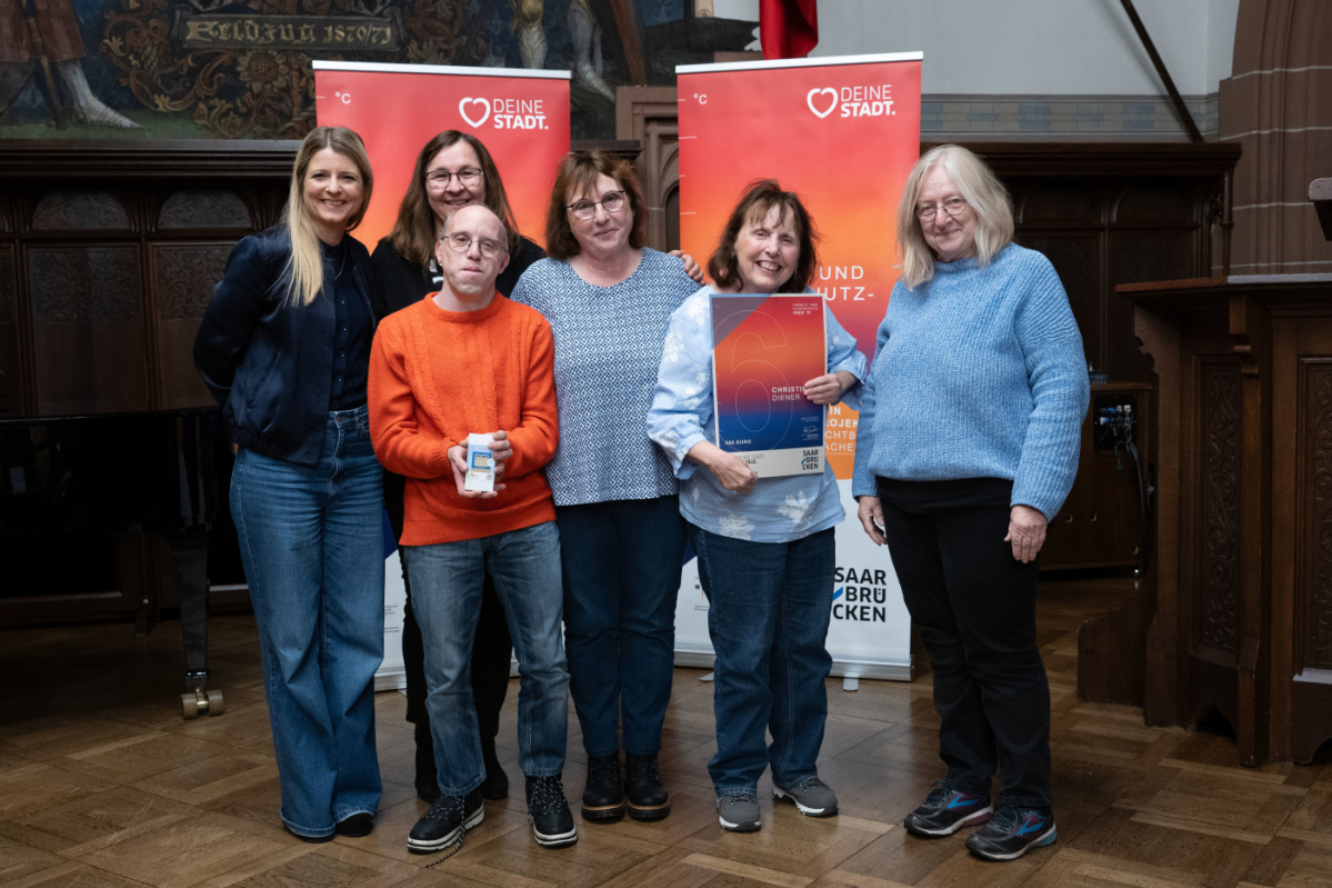 Preisträgerin und Begleitungen halten Urkunde in Kamera und lächeln