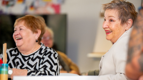 Zwei Seniorinnen sitzen lachend in einem Workshop