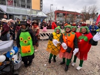 Mehrere verkleidete Frauen in Obstkostümen stehen lachend vor den Zuschauern hinter Absperrgittern