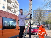 Ein Mann steht auf einer Leiter und entfernt Aufkleber auf Verkehrsschilder