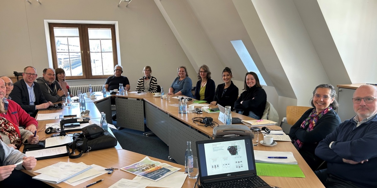 Sitzung der Arbeitsgruppe NEK/CTAR Frauen und Männer in einem Besprechungsraum mit Anschauungsmaterialien