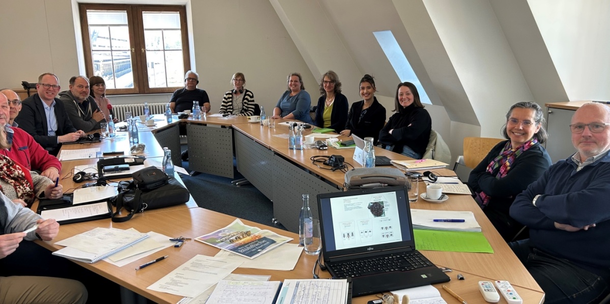 Frauen und Männer in einem Besprechungsraum mit Anschauungsmaterialien