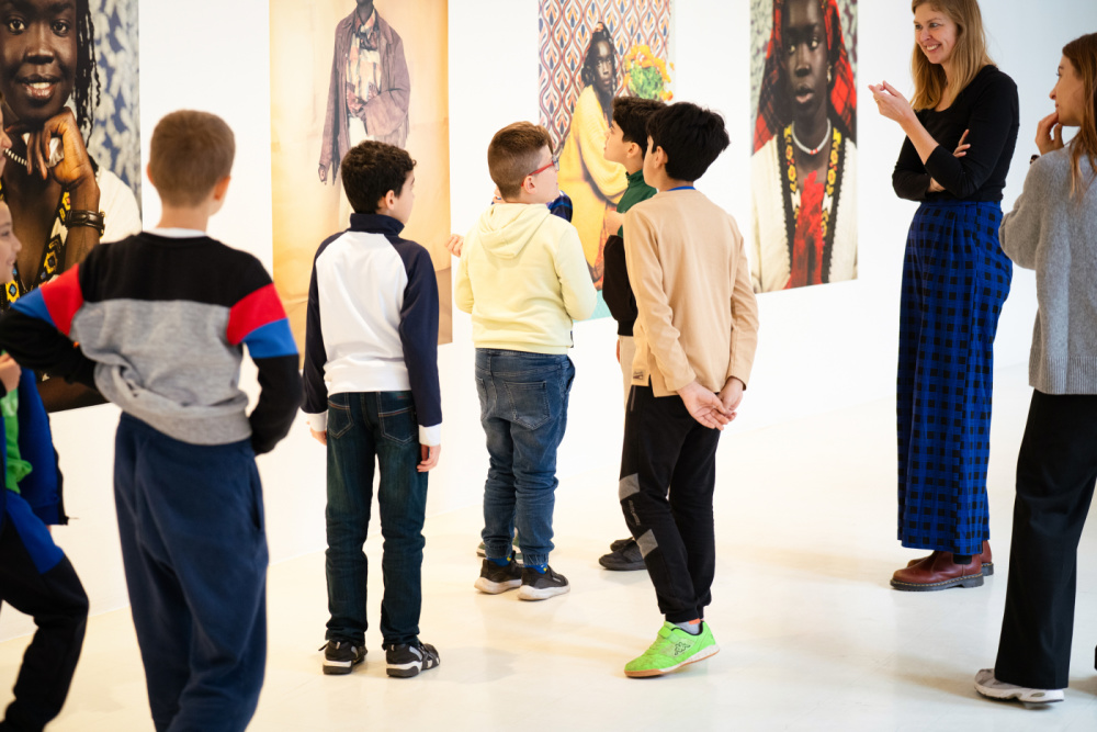 Eine Gruppe von Kindern schaut sich Fotos in einer Ausstellung an