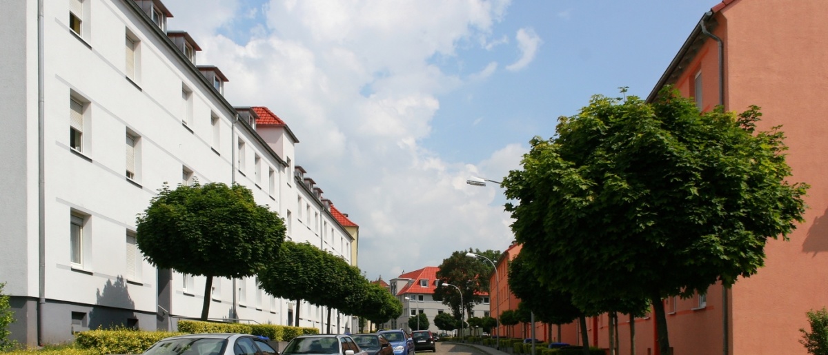 Straße mit Kopfsteinpflaster, links und rechts Wohnhäuser mit vier Etagen mit Satteldach
