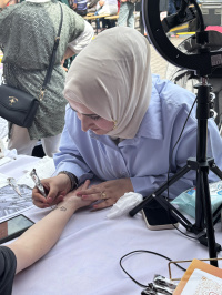 Eine Frau bemalt eine Hand mit Henna.