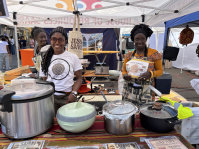 Zwei Frauen stehen hinter dem Stand mit dem afrikanischen Essen.